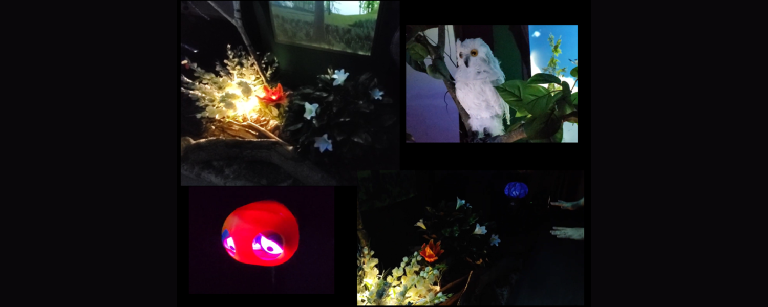 A dark room with video projections, animatronic objects, and an upside down umbrella displaying video of a blue sky and trees.
